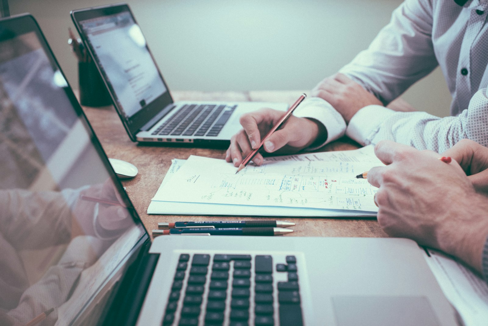 Professional consultation at a desk with documents and laptops